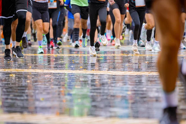 Ayakları ve bacakları düşük, büyük bir grup koşucu, atletler sokak maratonu yarışması, yağmurlu bir günde yarışan insan kalabalığı.