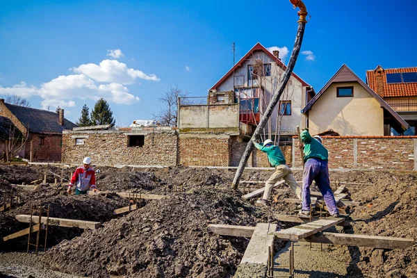 Zespół pracowników budowlanych pracują nad betonowania w konstrukcji — Zdjęcie stockowe