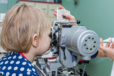 göz doktoru hastayla göz muayenesinde vererek