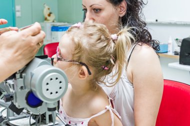 göz doktoru hastayla göz muayenesinde vererek