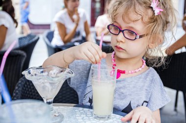 Küçük kız limonata restoranda içiyor.
