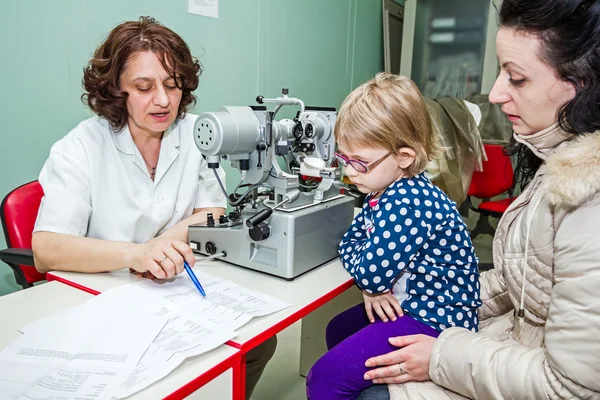 L'enfant est à l'examen des yeux à la clinique avec un équipement spécial . — Photo