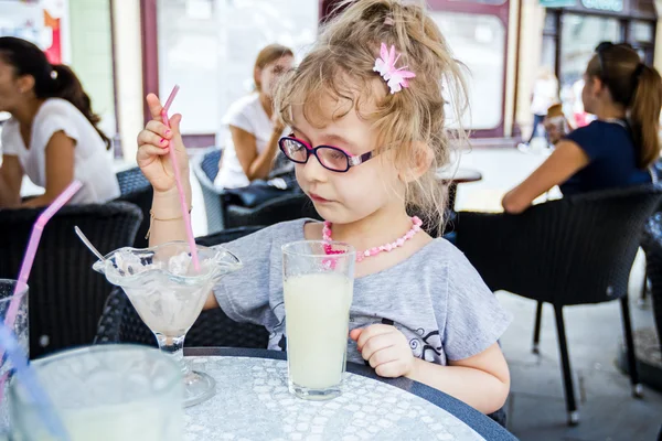 小さな女の子は、レストランでレモネードを飲んでいます。. — ストック写真