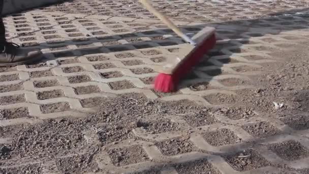 Trabajador está limpiando nuevo lugar de estacionamiento con escoba roja . — Vídeo de stock