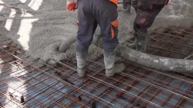 İşçiler beton takviyeli katta büyük inşaat alanı üzerinden yayılıyor.