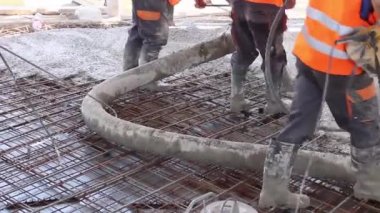 İşçiler beton takviyeli katta büyük inşaat alanı üzerinden yayılıyor.