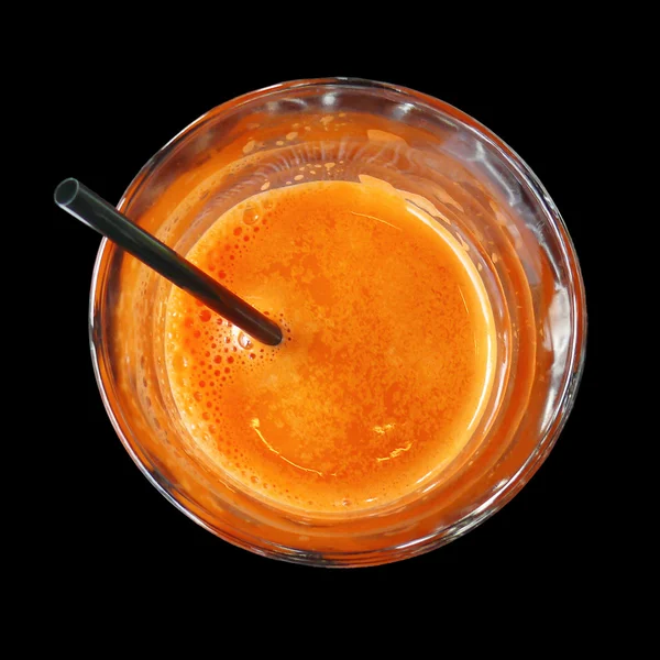 Fresh carrot juice in a glass - top view, isolated object on a black background