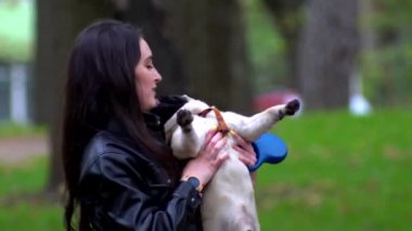 Genç kız şehir parkında bir köpekle oynuyor.