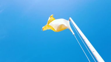 Sarı kare bir bayrak rüzgarda dalgalanıyor.