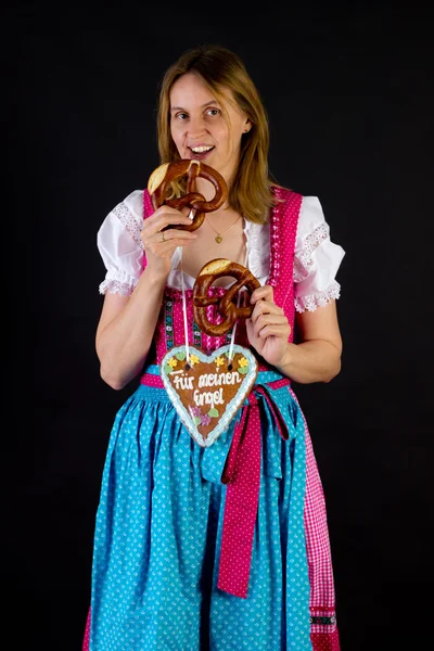 Woman in dirndl eating pretzel — Stock Photo, Image