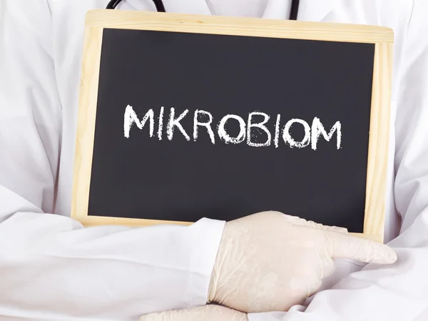 Doctor shows information: microbiome in german language — Stock Photo, Image