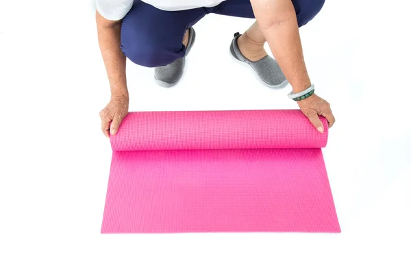 Tapete de ioga rosa rolando mão sênior — Fotografia de Stock