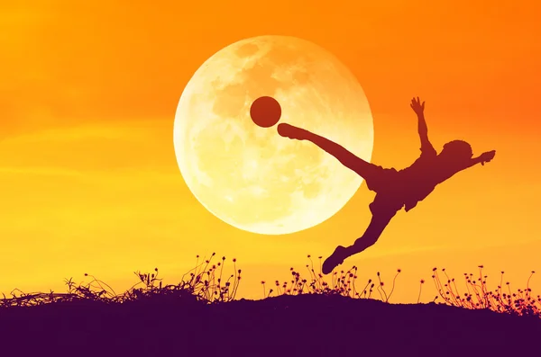 Silhouette dell'uomo del calcio che gioca con la palla e la luna grande . — Foto Stock