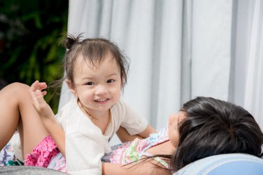 Şirin Asyalı kız kardeşiyle yatakta evde oynarken.