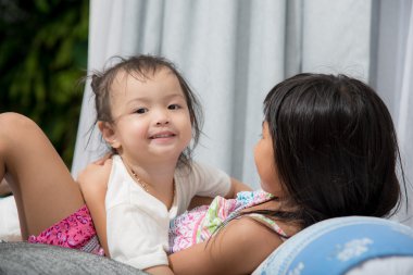 Şirin Asyalı kız kardeşiyle yatakta evde oynarken.