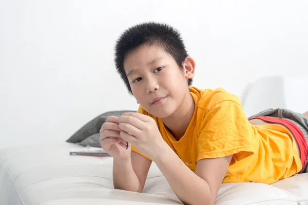 Asiatiska boy spelar lera på soffan hemma. — Stockfoto