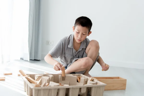 Un băiat asiatic care joacă o structură din blocuri de clădiri din lemn cu b — Fotografie, imagine de stoc