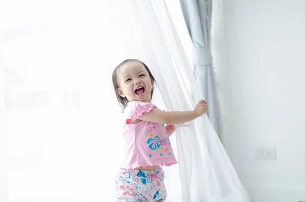 Asiática chica sosteniendo blanco cortina en casa . — Foto de Stock