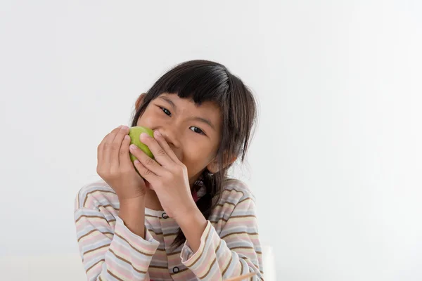 Chica asiática comiendo manzana verde sobre fondo gris — Foto de Stock