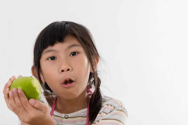Asijské dívky jíst zelené jablko na šedém pozadí — Stock fotografie