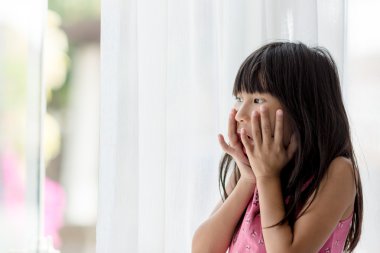 Pencereden dışarı bakıyor ve şaşırtıcı mutlu Asyalı kız