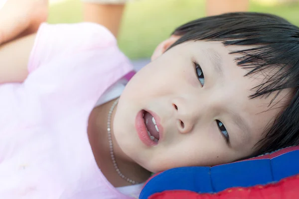 Menina asiática feliz que coloca com travesseiro ao ar livre . — Fotografia de Stock