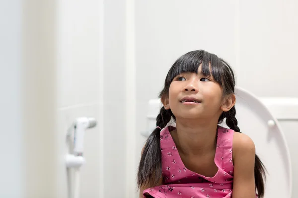 Menina asiática sentada no banheiro — Fotografia de Stock