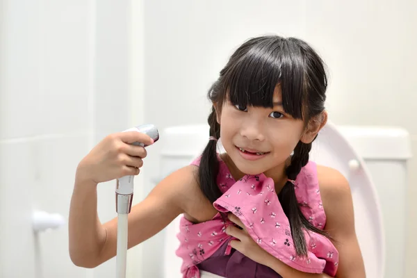 Asian girl sitting on toilet and using bidet — Stock Photo, Image