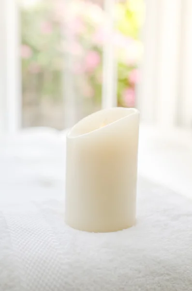 Big candle on towel next to window outdoor, depth of field. — Stock Photo, Image