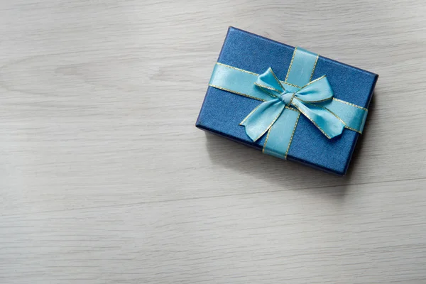 Blue gift box on gray wooden texture background with copyspace f — Stock Photo, Image