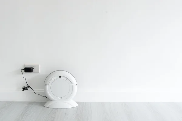 Cleaning robot charging at white wall with copyspace for display — Stock Photo, Image