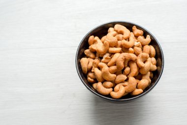 Gri ahşap masa üzerinde siyah seramik kase tuzlu kaju fıstığı