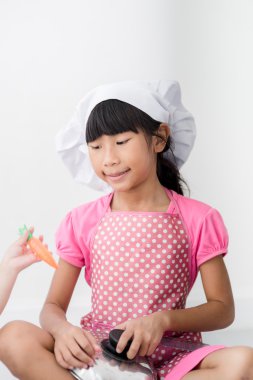 Asyalı çocuk evde aşçıyı oynuyor..