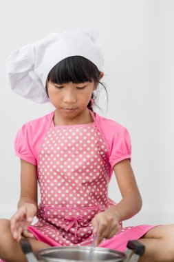 Asyalı çocuk evde aşçıyı oynuyor..