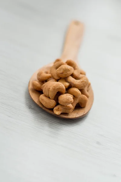 Salta cashewnötter i trä sked på grå träbord — Stockfoto