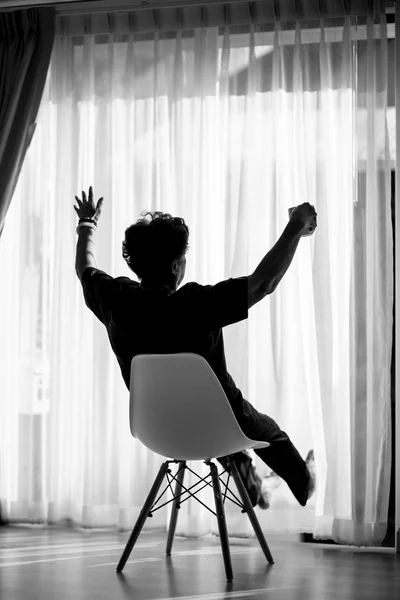 Preto e branco mulher em casa sentado na cadeira moderna na frente o — Fotografia de Stock