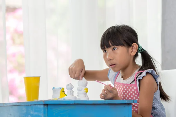 Asijské dítě maluje barvy bílé sádry panenka hračky na — Stock fotografie