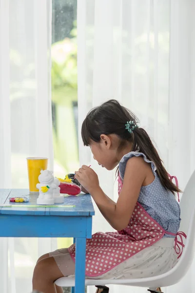 Asiatico bambino dipinge i colori di bianco gesso bambola giocattoli sul — Foto Stock