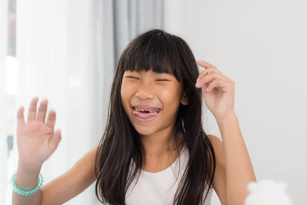 Schattig gelukkig meisje lachen en tonen haar vervallen tanden thuis. — Stockfoto