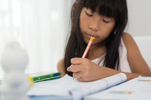 Süße asiatische Mädchen schreiben Hausaufgaben auf ein Buch zu Hause — Stockfoto