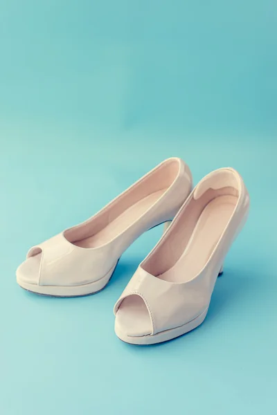 Pastel beige schoenen geïsoleerd op blauwe achtergrond. — Stockfoto