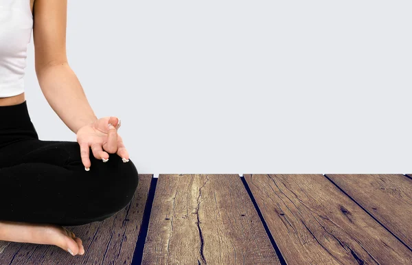 Mujer joven haciendo meditación sobre suelo de madera y fondo gris — Foto de Stock