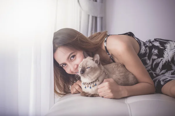 Asian woman and cat laying on sofa with window light. — Stock Photo, Image