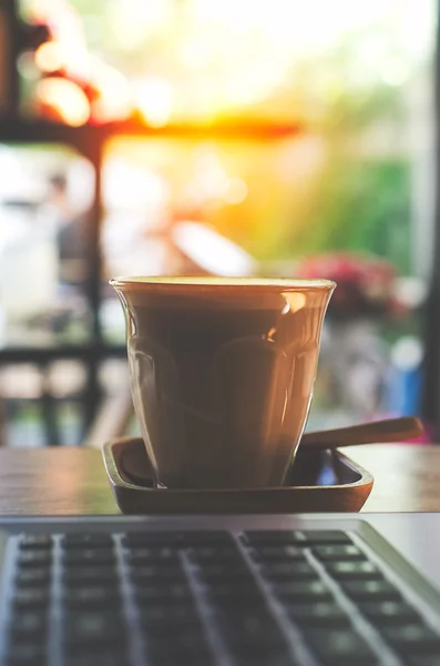 Taza de café y computadora portátil para negocios, enfoque selectivo en el café —  Fotos de Stock