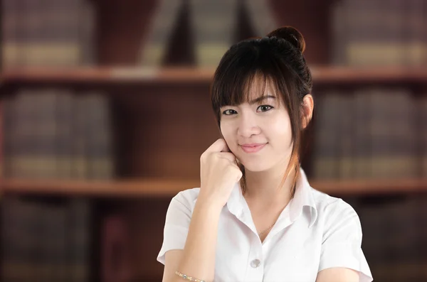 Estudante asiático em uniforme com fundo de biblioteca embaçada, educati — Fotografia de Stock