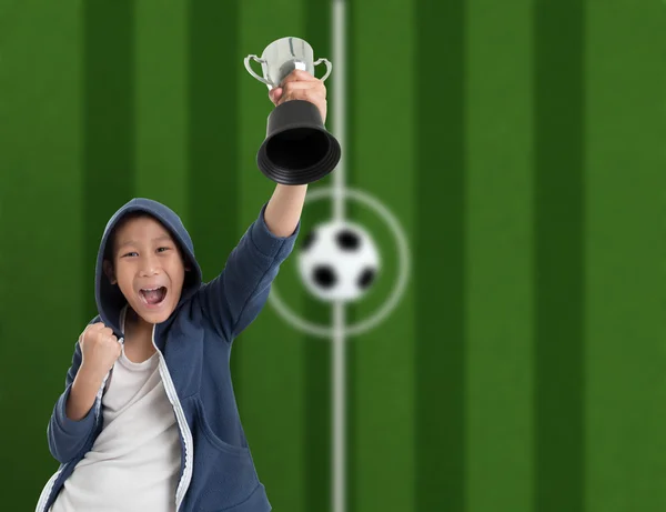 Młody chłopak sobie Błękitna Kurtka kaptur i przytrzymując piłkarskie trofeum — Zdjęcie stockowe