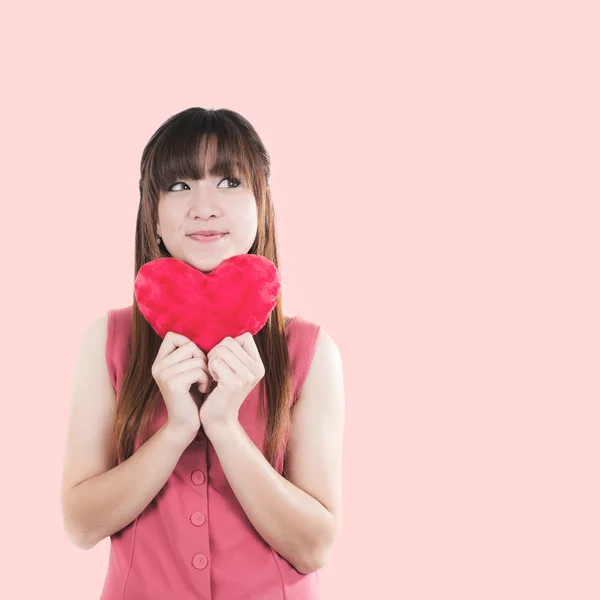 Feliz asiática joven mujer sosteniendo pequeño rojo corazón forma almohada iso — Foto de Stock