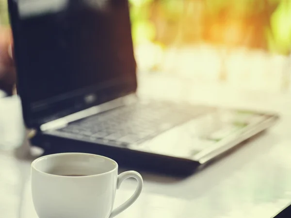 Taza de café y computadora portátil para negocios, enfoque selectivo en el café . —  Fotos de Stock