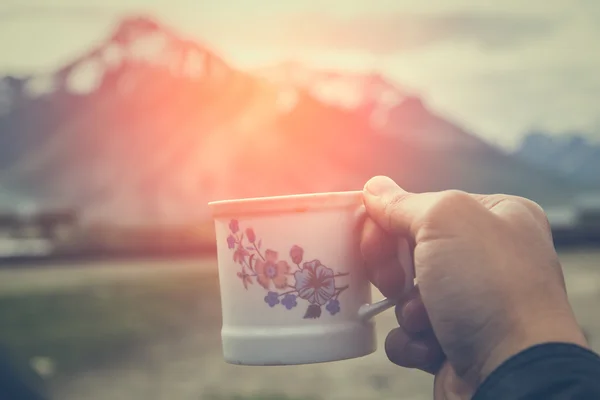 Mano sosteniendo una taza de té masala chia con luz cálida y Himala —  Fotos de Stock