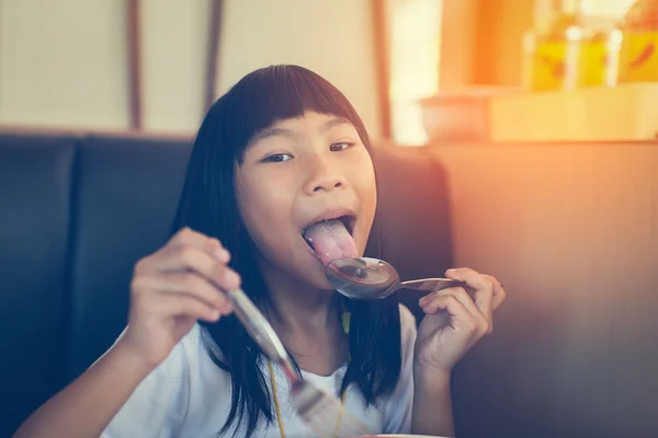 Girl licking her spoon in cafe — Stock Photo, Image